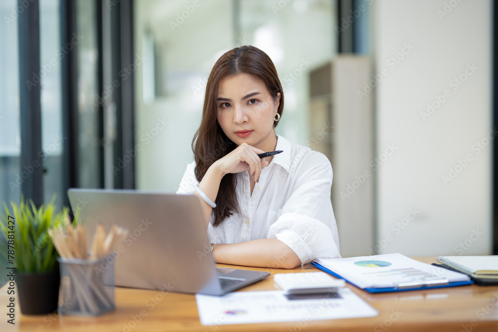 Concerned businesswoman in deep thought, facing work challenges while at her laptop in a busy office environment. Concerned businesswoman in deep thought, facing work challenges while at her laptop in a busy office environment.