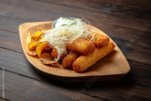  Cheese sticks with potato chips on dark boards background. Menu for a pub