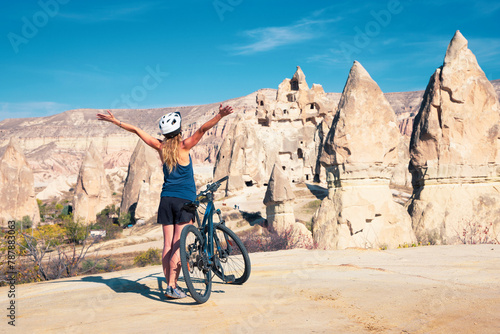happy woman with arms up and mountain bike (Cappadocia)
