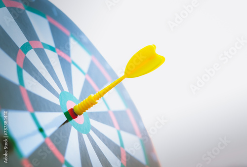 Close up yellow dart arrow hitting target center dartboard on sunset background. Business targeting and focus concept.