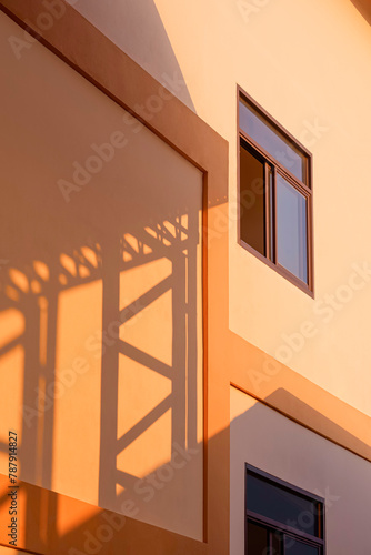 Light and shadow of metal warehouse column on orange concrete wall surface of industrial office building in vertical frame, perspective side view and minimal style © Prapat