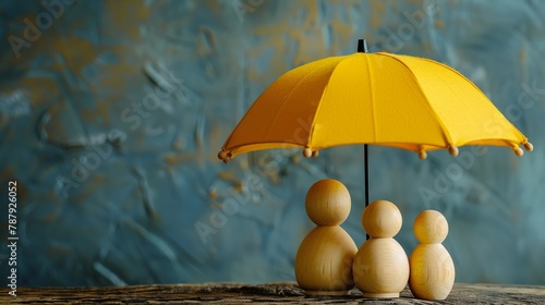 Wooden doll family under yellow umbrella, coverage concept, room for text