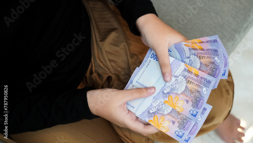 A young girl is sitting on a couch and holding a stack of bills.