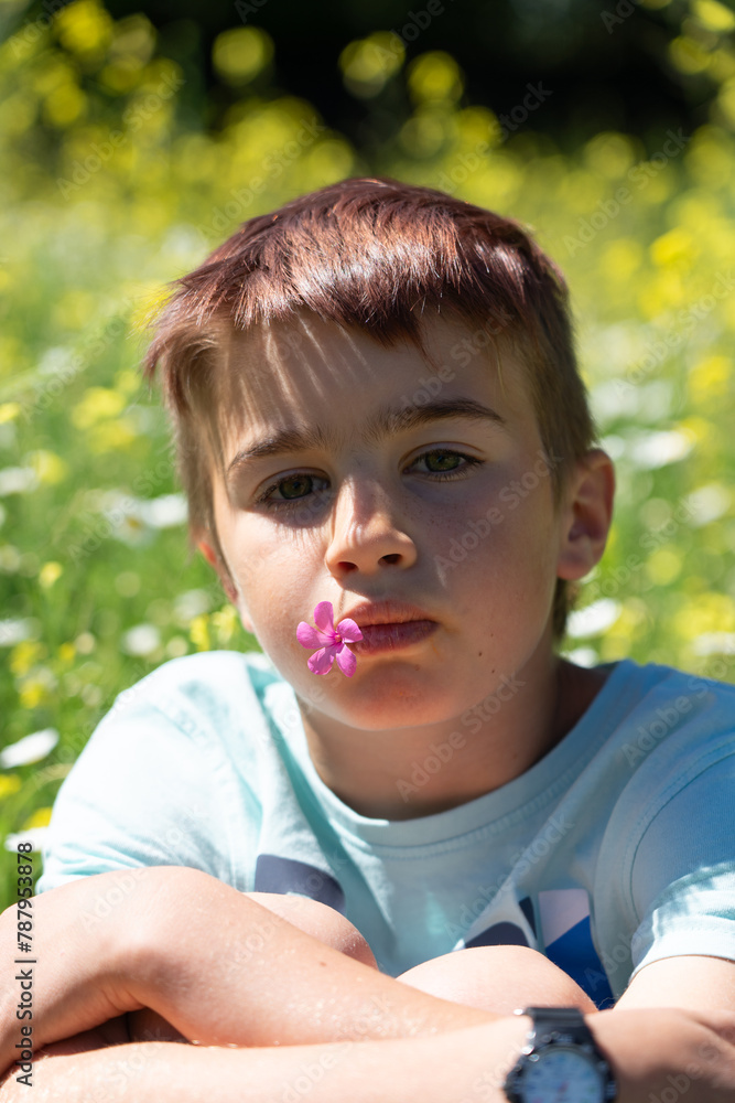 Portrait of caucasian boy in spring outdoors with a flower in his mouth Portrait of caucasian boy in spring outdoors with a flower in his mouth