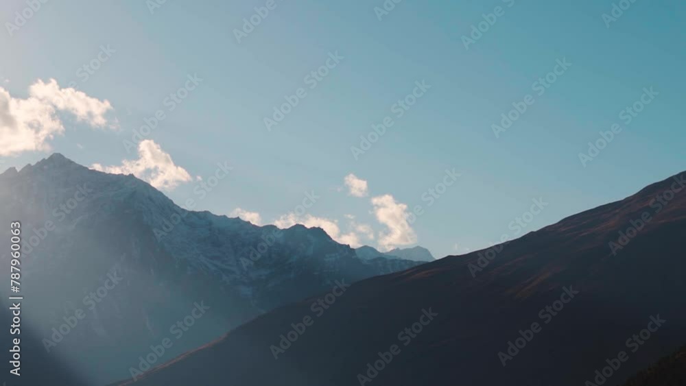 Sun rays through the clouds above the snowy Himalayan mountain peak ...