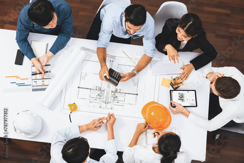 Top view banner of diverse group of civil engineer and client working together on architectural project, reviewing construction plan and building blueprint at meeting table. Prudent