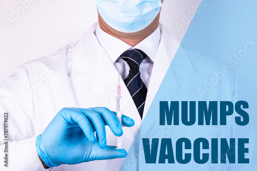 Mumps Vaccine text is written on the background of a doctor who is holding a syringe with a vaccine in a medical mask and gloves. Medical concept.