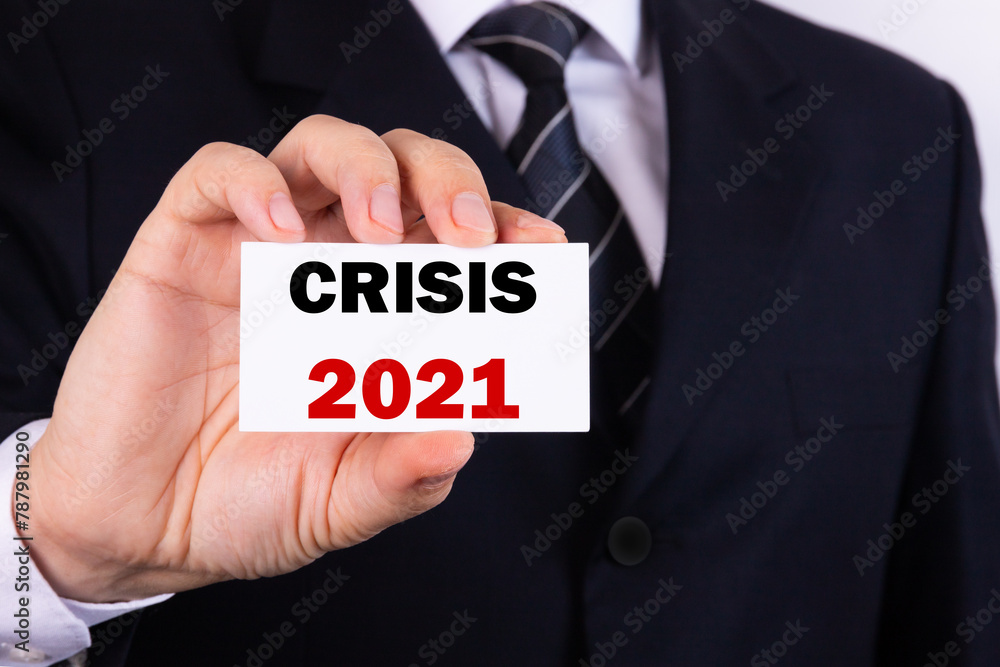 A businessman is holding a tablet with the text Crisis 2021 in front of him in his hands. Business concept A businessman is holding a tablet with the text Crisis 2021 in front of him in his hands. Business concept