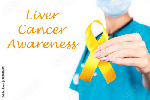 Liver cancer awareness concept. A doctor in blue clothes with a yellow ribbon in her hand, as a symbol of awareness photo