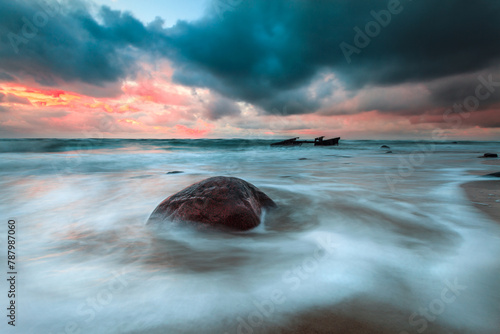 Stormy sunset over rough sea and rocky beach, Lithuania
