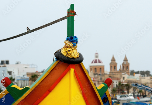 Close-up of a traditional luzzu with cityscape in background, Marsaxlokk, Malta photo