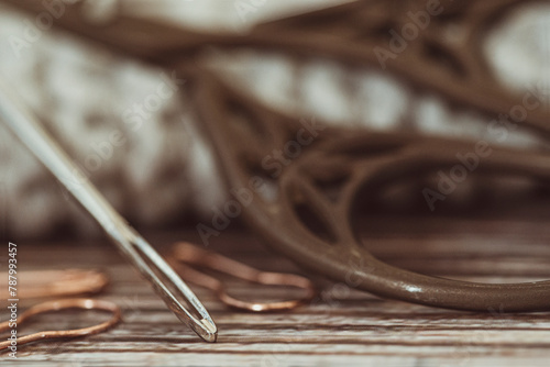 Close-up of vintage scissors and a sewing needle on a table photo