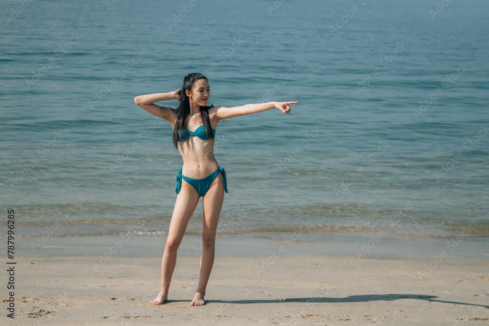 young woman in bikini posing pointing on the beach young woman in bikini posing pointing on the beach