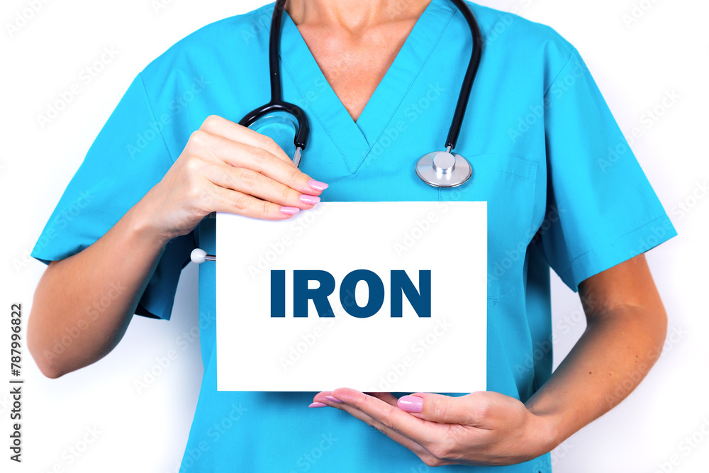 A doctor in a blue medical uniform is holding a tablet with the text IRON. Medical concept. A doctor in a blue medical uniform is holding a tablet with the text IRON. Medical concept.