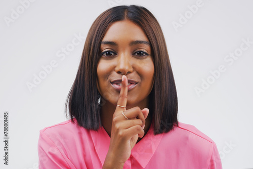 Indian woman, finger on lips and portrait in studio for secret news, privacy and gossip for confidential. Young people, hush gesture and emoji or sign for silent, quiet or smile for mysterious shush photo