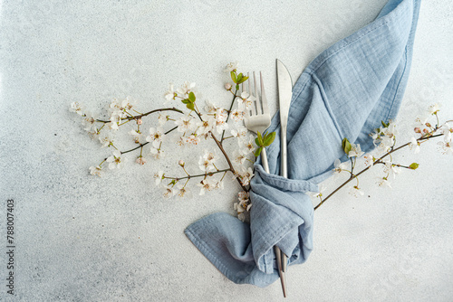 Overhead view of a cutlery setting with a napkin and cherry blossom branches in full bloom on a table photo