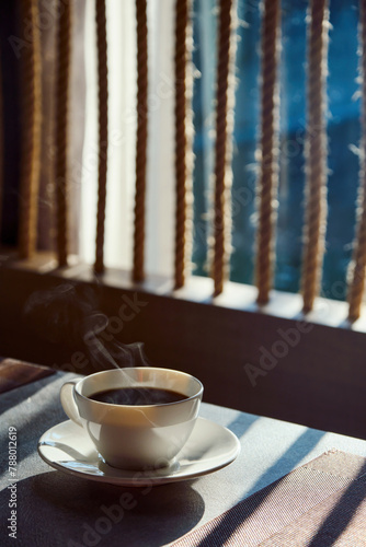 a morning hot coffee in white cup in sunshine scene with shade and white smoke from hot water