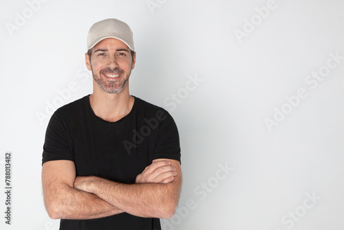 Hombre sonriente con los brazos cruzados. Emprendedor. Marketing online. Chico con gorra, camiseta negra y fondo blanco. Venta online.