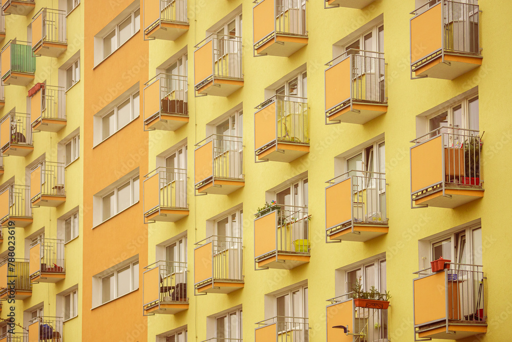 Żółto-pomarańczowa elewacja bloku mieszkalnego z wieloma balkonami. Styl lat siedemdziesiątych.  - obrazy, fototapety, plakaty 