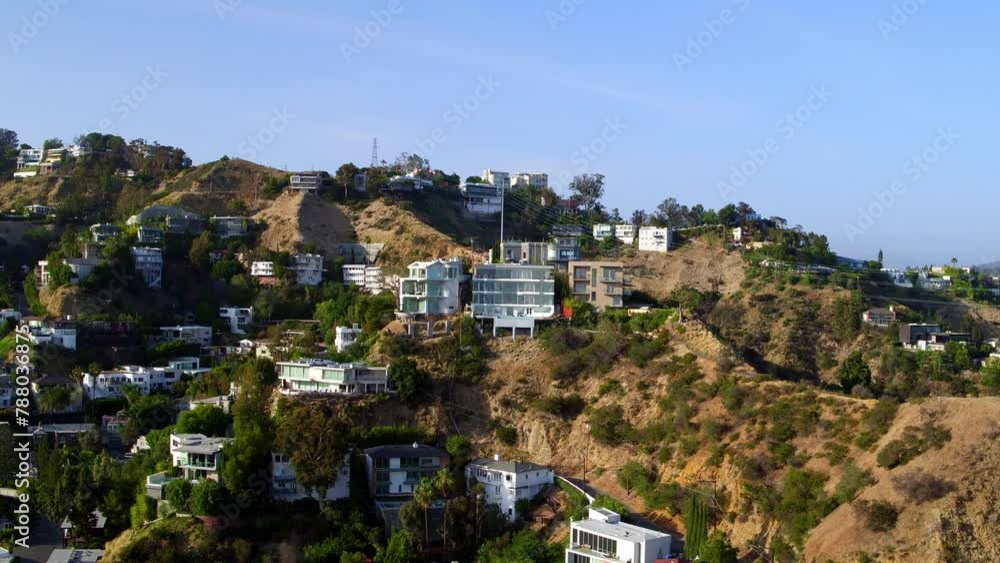 Aerial Panning Shot Of Houses On Hills With Plants In Neighborhood Against Blue Sky - Los Angeles, California Aerial Panning Shot Of Houses On Hills With Plants In Neighborhood Against Blue Sky - Los Angeles, California