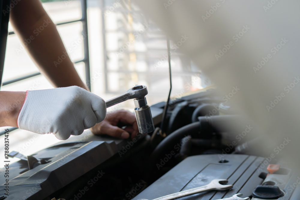 Fototapeta premium Mechanic using wrench while working on car engine at garage workshop, Car auto services and maintenance check concept.