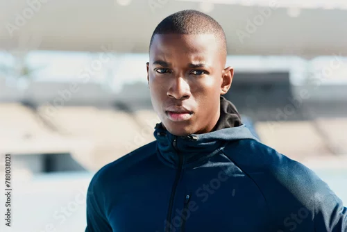 Obraz Portrait, black man and athlete at race track for sports, wellness or exercise for body health in Kenya. Face, serious person and runner at stadium for fitness, workout or training outdoor in Africa