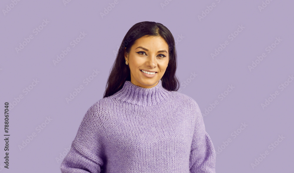 Studio shot of young woman in warm sweater. Portrait of happy beautiful young brunette girl in purple woolen sweater standing on lavender background, looking at camera and smiling. Fashion concept Studio shot of young woman in warm sweater. Portrait of happy beautiful young brunette girl in purple woolen sweater standing on lavender background, looking at camera and smiling. Fashion concept