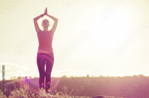 Young woman practicing yoga outdoors with a sunset background 