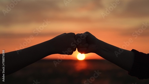 Hands clashing fists brofist at sunset in field. Farmers workers colleagues employees partners working in agricultural field lawn glade on farm hit fists shake hands interact. Teamwork friendship.