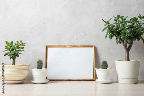 Template with photo frame on a wooden table. Houseplants in a pots.