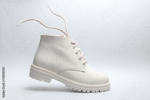White leather boot with flying laces on a gray background.