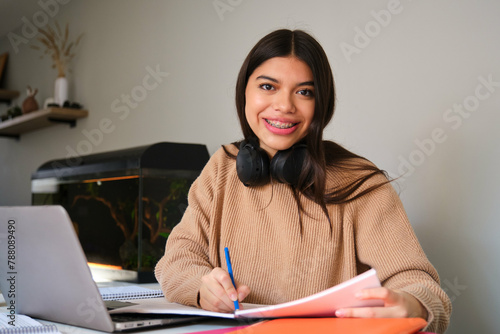 Portrait of a smiling female college student with braces studying at home. © Ladanifer