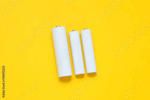 White blank aa and aaa batteries or accumulators on a yellow background. Mockup for design photo