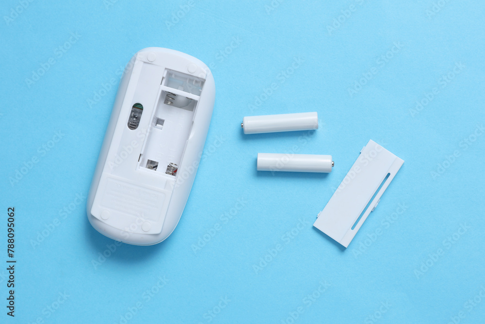 Wireless PC mouse and batteries on a blue background Wireless PC mouse and batteries on a blue background