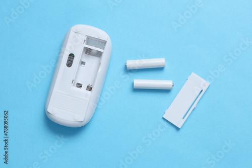 Wireless PC mouse and batteries on a blue background