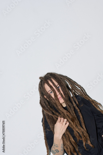 At angle portrait of Caucasian woman with long dreadlocks hairstyle looking at camera on white shot with flash copy space © Mediaphotos