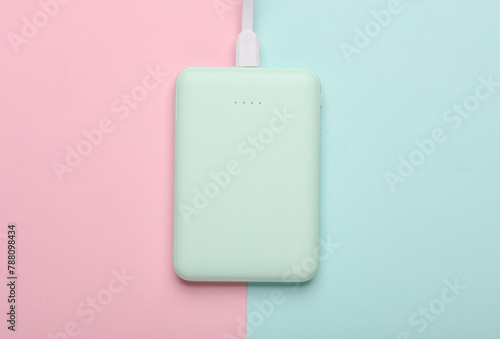 Plastic power bank mint green color on pink blue pastel background. Top view
