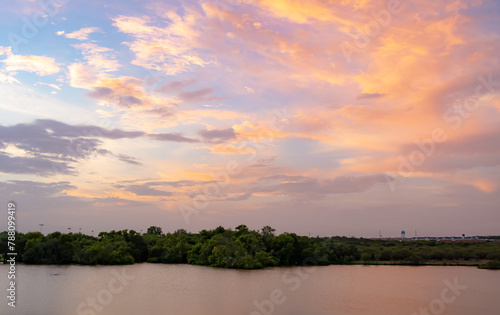 Dramatic sunset clouds reflection along the treelined horizon  on Woodlawn Lake San Antonio Texas