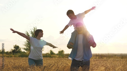 Mother father and son playing flying fantasy at sunset bright sun dry wheat field. Happy family running imagination together enjoy freedom outdoor with positive emotion at harvest cereal plantation