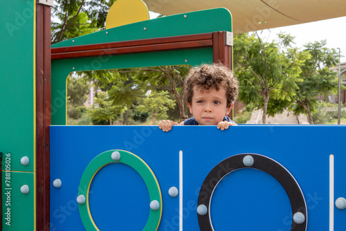 Curly-Haired Boy Peeking Over Playground