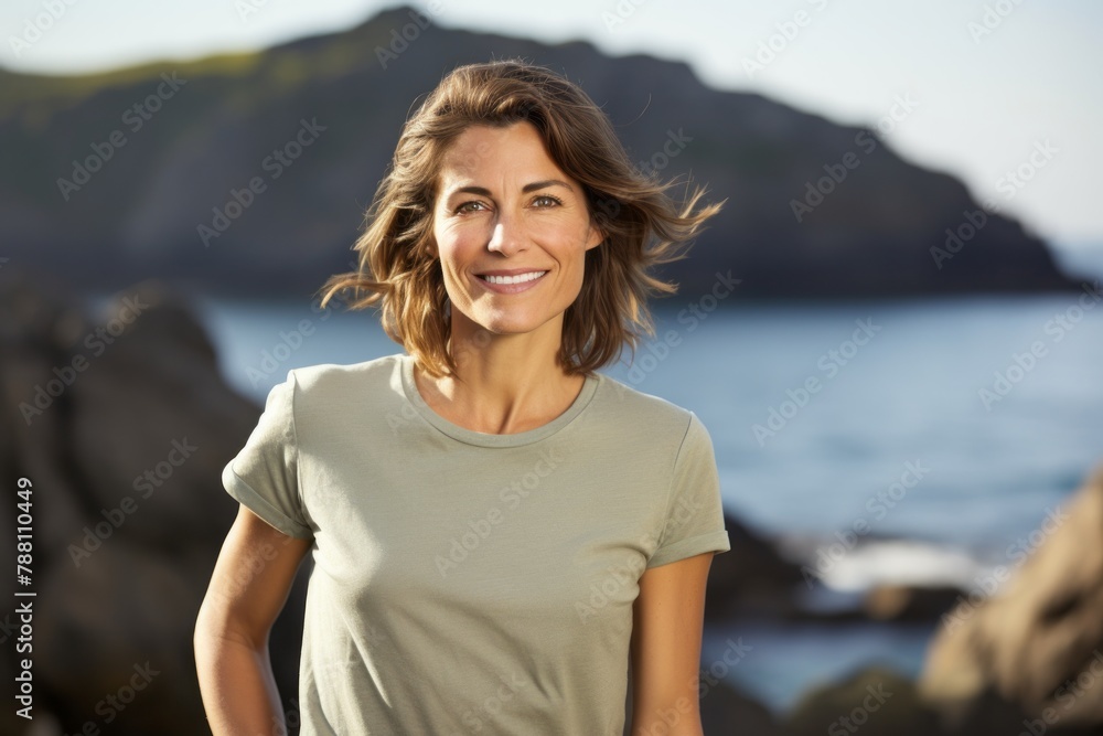 Portrait of a satisfied woman in her 40s dressed in a casual t-shirt isolated on rocky shoreline background Portrait of a satisfied woman in her 40s dressed in a casual t-shirt isolated on rocky shoreline background