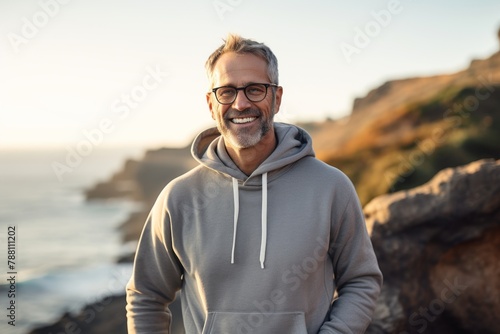 Portrait of a smiling man in his 50s dressed in a comfy fleece pullover isolated in rocky shoreline background