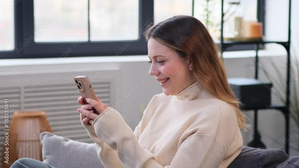 Smiling Caucasian woman messaging in social media or surfing internet and laughing using phone at home living room. Resting online. Smiling Caucasian woman messaging in social media or surfing internet and laughing using phone at home living room. Resting online.
