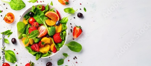 A healthy meal of fresh salad containing fruits and vegetables, displayed from a top perspective on a white background with room for text.
