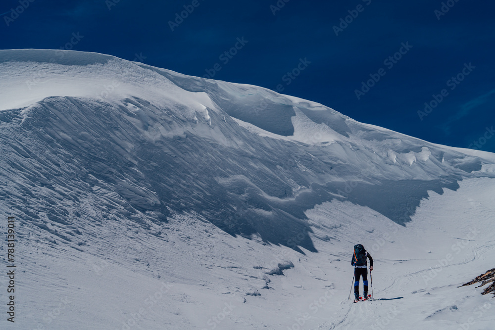 Athletes doing backcountry ski with a landscape of snowy mountains on a sunny day. Sunset over the snowy mountains.