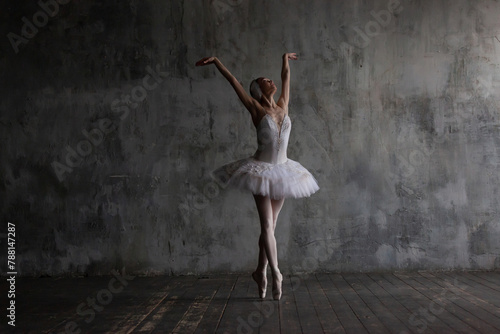 Ballerina in a white tutu dances the part of the white swan from Tchaikovsky's ballet Swan Lake.