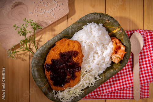 japanese food with recycle biodegradable leaf plate. tonkatsu with rice is an asian food top with japanese tonkatsu sauce and korean kimchi serve on bio organic green leaf dish with disposable later