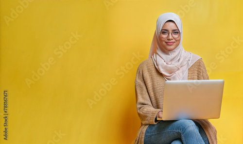 Wallpaper Mural Muslim woman wearing hijab working on a laptop on a clean yellow background with copy space Torontodigital.ca