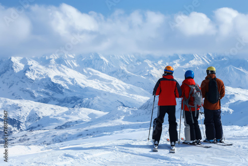 Trio of skiers pauses high on a snowy peak to enjoy the stunning mountain view