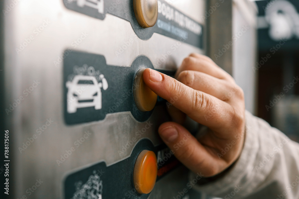 Close up of a hand pressing a button on a self-service coin machine at car wash - obrazy, fototapety, plakaty 